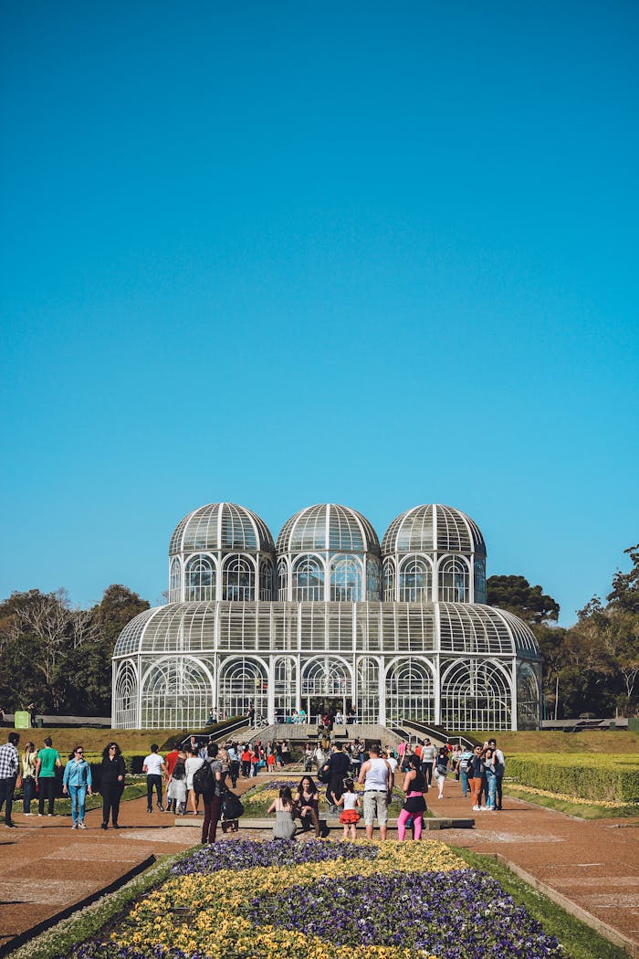 Vibrant botanical garden scene in Brazil with iconic glasshouse and visitors under a blue sky.